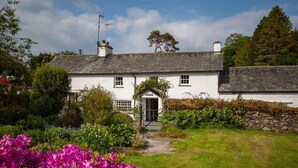 A white cottage with a stone wall and a garden with pink flowers. - The Old Farm (Ambleside)