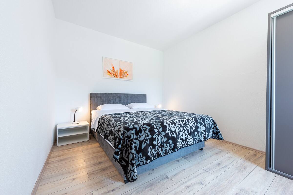 Ein modernes Schlafzimmer mit einem Bett, Nachttischen und einem Wandbild.