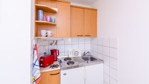 Eine kleine Küche mit Holzschränken, einer weißen Fliesenspiegel und einem roten Toaster, einer Kaffeemaschine und einem Wasserkocher.