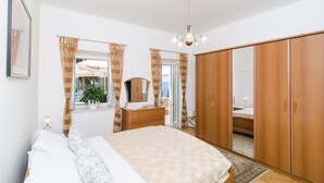 Ein Schlafzimmer mit einem Bett, einem Schminktisch, einem Spiegel, einem Kleiderschrank und einem Fenster mit Vorhängen.
