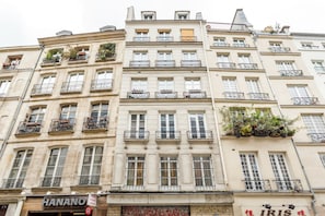 A multi-story building with balconies, a visible storefront named 'HANANO', and another with 'IRIS' signage. - Merveil -Luxury Serviced Apartment-Saint Martin II (Paris)