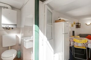 Una cocina pequeña con un refrigerador blanco, un lavamanos y una ventana.