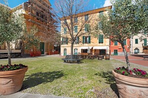 Un patio con un banco, plantas en macetas y un edificio con múltiples ventanas y balcones.