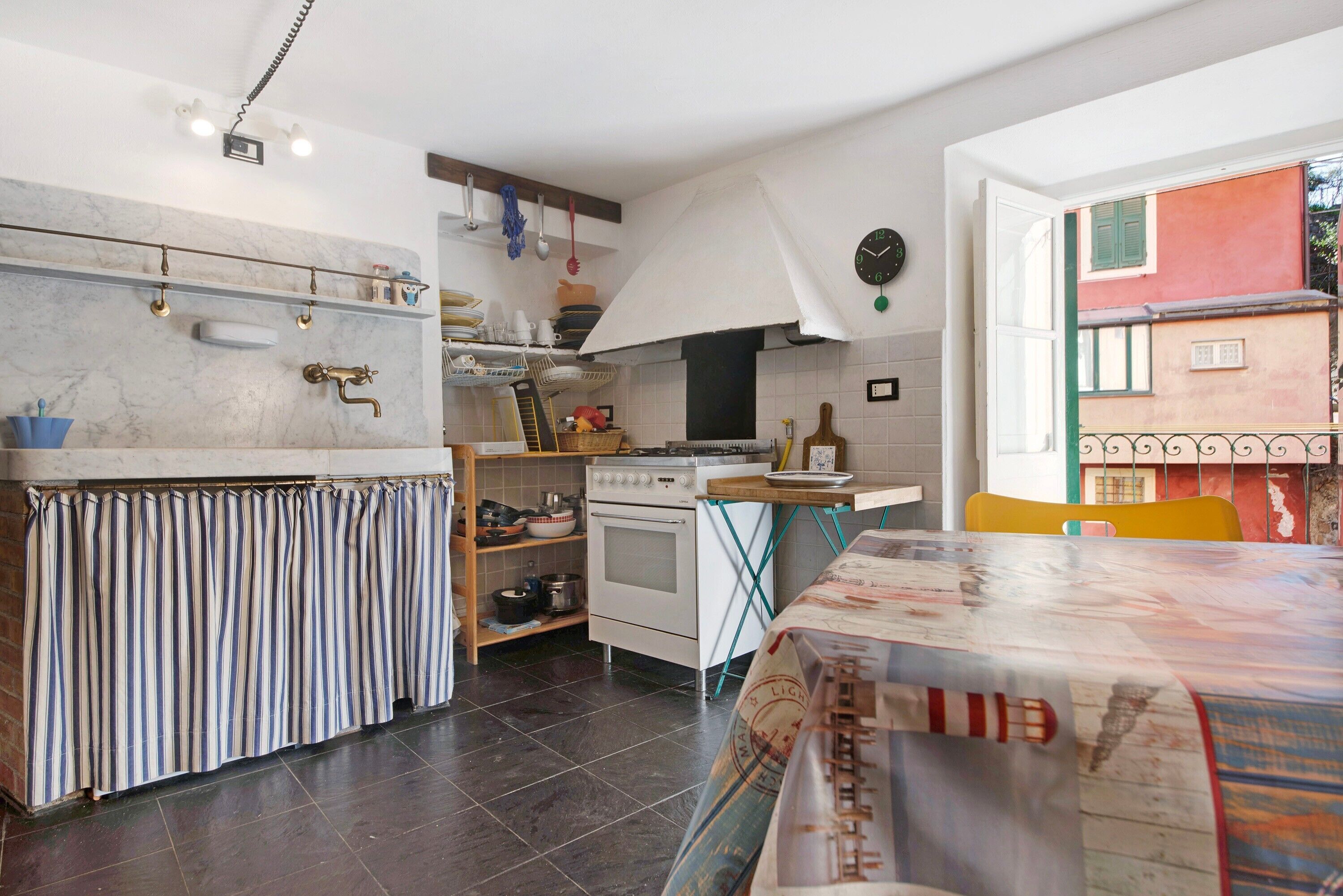 Una cucina con fornello, forno e utensili appesi.