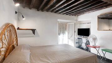 Una camera da letto con un letto, una televisione, un ventilatore e una macchina da cucire.