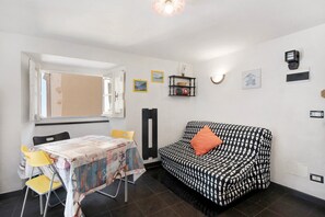 Una habitación con cama, una mesa y sillas, una ventana y luces fijadas a la pared.