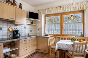 A kitchen with wooden cabinets, a coffee maker, a TV, and a window with a view of trees.