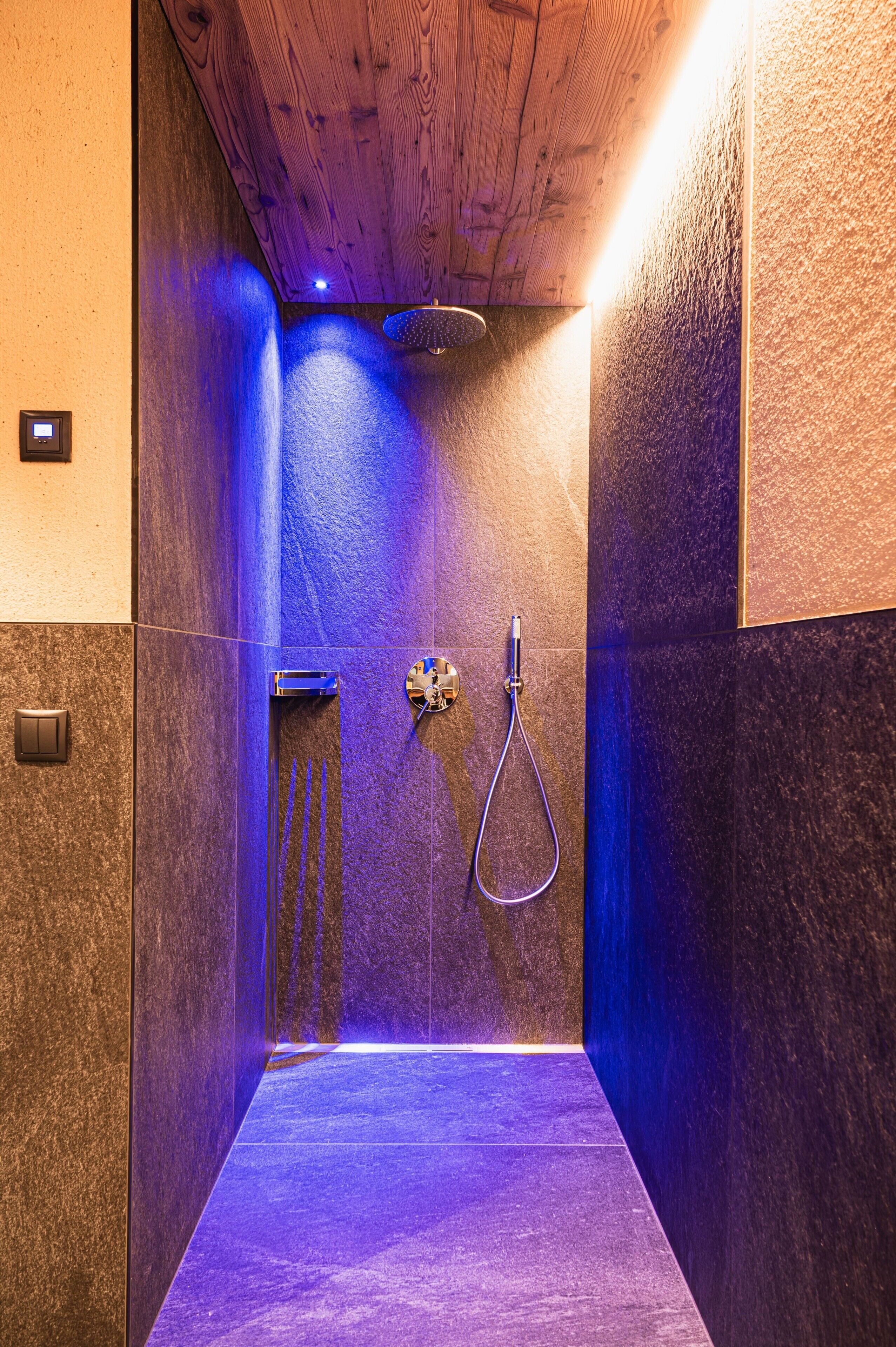 Une douche moderne avec un plafond en bois et des murs à texture.