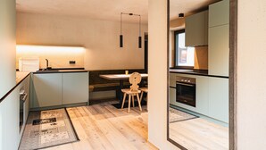 Une cuisine moderne avec un îlot central, des chaises en bois, des luminaires suspendus et un grand miroir.