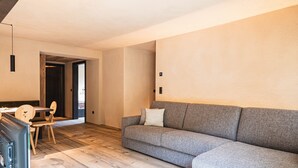 Un salon moderne avec un canapé gris, un plancher en bois et un téléviseur.