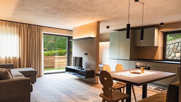 Un salon moderne avec un canapé, un téléviseur et un coin repas équipé de chaises.