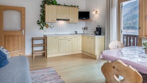 A compact kitchen with wooden cabinets, a built-in TV, and a window with a mountain view. - Apartment 'Adlerhorst Rotkehlchen' with Balcony, Shared Garden and Wi-Fi (Santa Valburga)
