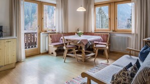 A cozy room with a dining table, chairs, a sofa, and large windows with curtains. - Apartment 'Adlerhorst Rotkehlchen' with Balcony, Shared Garden and Wi-Fi (Santa Valburga)