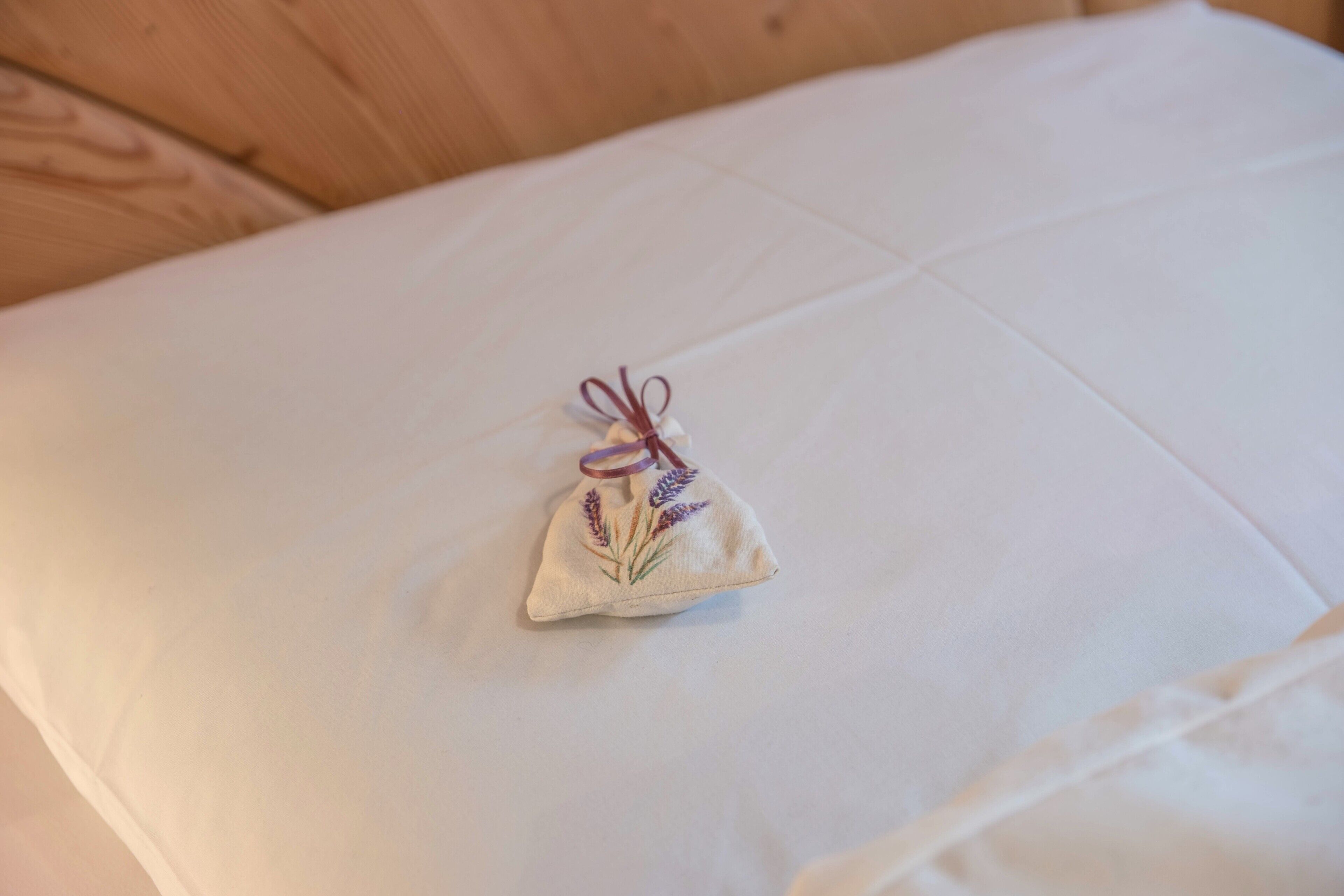 A small decorative item on a bed with a white sheet.