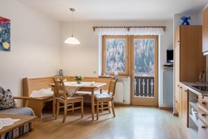 Una habitación acogedora con una mesa de madera, sillas, un sofá, un televisor y una ventana con vistas a árboles.