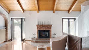 A room with a fireplace, a bed, a chair, and a large window.