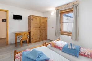 A bedroom with two beds, a wooden wardrobe, a desk, and a TV. - Holiday Apartment "Vacanze Matteo" with Mountain View, Balcony & Wi-Fi (Livigno)