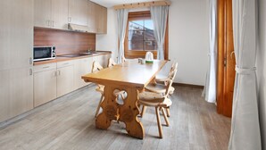 A modern kitchen with wooden cabinets, a wooden dining table, and chairs.