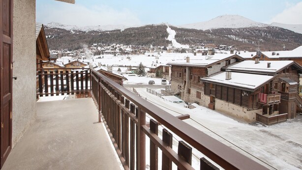 A balcony with a view of a snow-covered village and mountains.