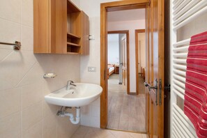 Un baño con un mueble de madera, un lavabo blanco y un perchero para toallas.