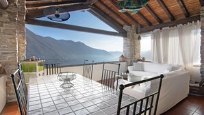 A room with a tiled table, white sofa, and a view of mountains. - Holiday Home 'Stone House Of The Year 1500' with Lake View, Private Terrace and Wi-Fi (Moltrasio)