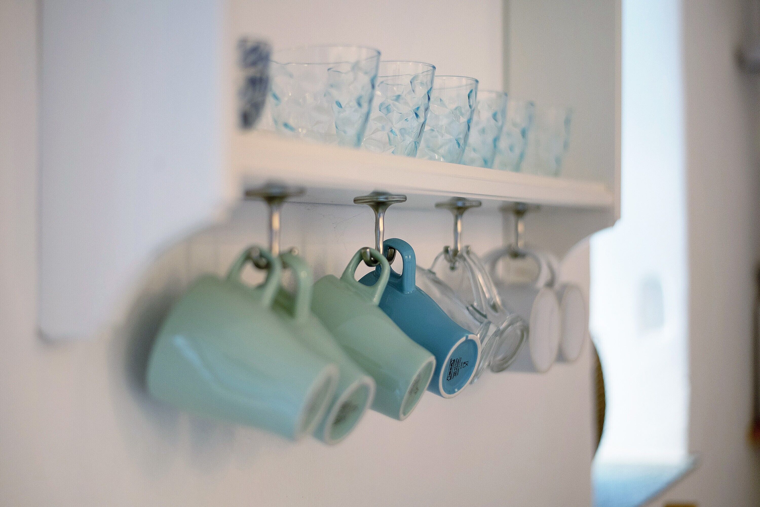 A wall-mounted shelf with various glassware and mugs.