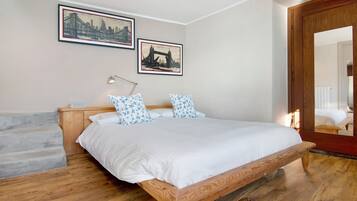 Un dormitorio con una cama de madera, una mesita de noche, una lámpara y dos cuadros en la pared.