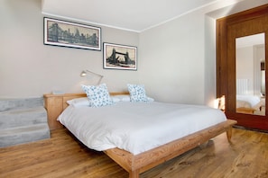 A bedroom with a wooden bed, a nightstand, a lamp, and two framed pictures on the wall. - Apartment "Renovated Barn of the year 1500" with Lake View & Wi-Fi (Moltrasio)