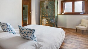 Un dormitorio con una cama, un armario de madera, una silla y una ventana.