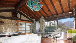 Un intérieur rustique avec un mur en pierre, des poutres en bois, un canapé blanc, une table à manger avec des chaises et une sculpture de poisson.
