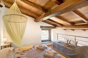 Une chambre à coucher avec un lit à baldaquin, une fenêtre et un lit séparé doté d’une tête de lit.