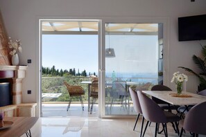 A modern dining area with a view of the landscape, a TV mounted on the wall, and a table with chairs. - "Villa Nefeli" with Sea View, Private Pool & Wi-Fi (Lefkada)