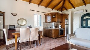 Un salon avec un canapé, une table à manger avec des chaises, un coin cuisine avec des meubles en bois et un sol carrelé.