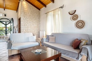 A living room with a stone wall, two sofas, a coffee table, and a window with curtains.