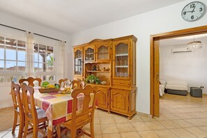 Un coin repas avec une table et des chaises en bois, un buffet en bois doté de portes en verre et une horloge au mur.