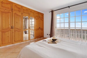 Een slaapkamer met een groot bed, een houten garderobe en een balkon met uitzicht.