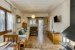 Ein Wohnzimmer mit Sofa, Sessel, Esstisch und Kamin.