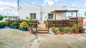 A two-story building with a wooden fence, potted plants, and a concrete driveway. - Holiday Home "de l'avi" with Pool, Garden & Wi-Fi (Camarles)