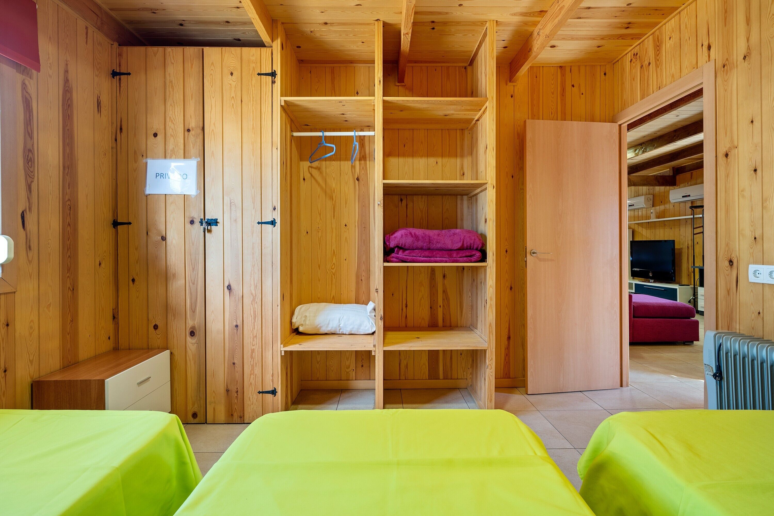 A wooden room with a bed, a wardrobe, and a radiator.