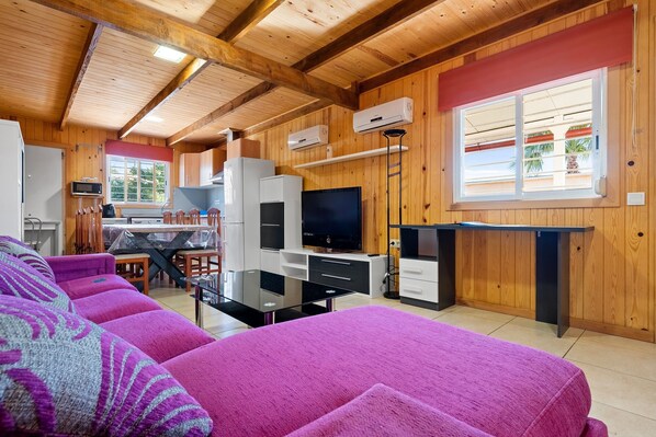 Ein Zimmer mit Holzwänden, einer Couch, einem Fernseher und einer Küchenzeile.