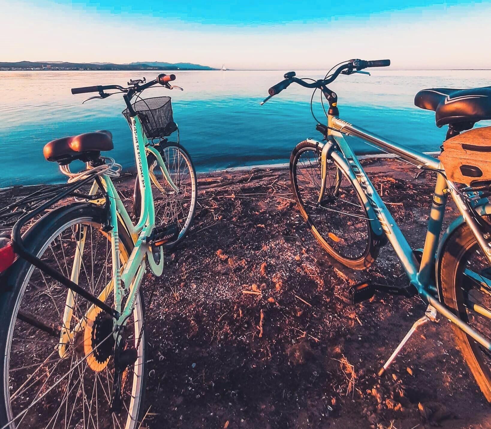 Twee fietsen geparkeerd op een rotsachtige kust met uitzicht op zee en het land in de verte.