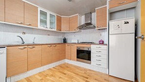 A kitchen with wooden cabinets, a stainless steel range hood, a built-in oven, and a white refrigerator. - Holiday Home "La Marquesa" with Shared Pool, Garden & Wi-Fi (Camarles)
