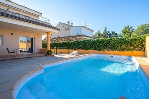 A swimming pool with a sunlit patio area, a covered seating area, and a hedge. - Holiday Home "Chalet l'alba" with Pool, Garden & Wi-Fi (deltebre)