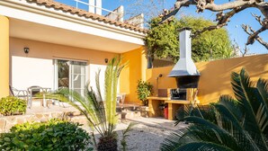 Une terrasse avec des meubles d’extérieur, un barbecue et un chemin en pierre.