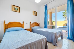 A bedroom with two beds, a window with blue curtains, and a view of the outside. - Holiday Home "Chalet l'alba" with Pool, Garden & Wi-Fi (deltebre)