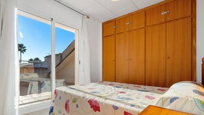 Une chambre à coucher avec un lit, une armoire en bois et une porte-fenêtre coulissante donnant sur l’extérieur.