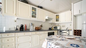 A kitchen with white cabinets, a microwave, a coffee maker, and a table with a patterned tablecloth. - 2-Star Apartment "Chez Domi résidence front de mer" with Terraces & Wi-Fi (Frontignan)