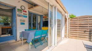 A patio area with a table and chairs, a television, and a clock on the wall. - 2-Star Apartment "Chez Domi résidence front de mer" with Terraces & Wi-Fi (Frontignan)