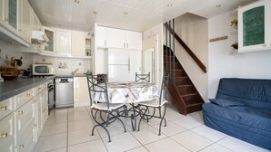 A kitchen with white cabinets, a dining table, and a blue sofa. - 2-Star Apartment "Chez Domi résidence front de mer" with Terraces & Wi-Fi (Frontignan)