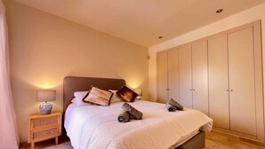 Ein Schlafzimmer mit Bett, Nachttisch, Lampe und Kleiderschrank.